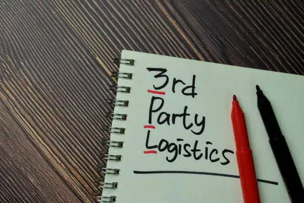 Notebook with the phrase “3rd Party Logistics” written beside red and black pens on wooden table