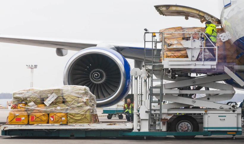 Ground crew loading palletized cargo into an aircraft for air freight shipping from China to Jamaica