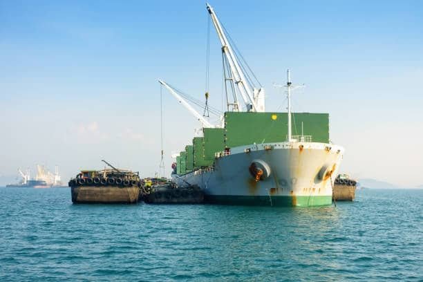 Large cargo ship transferring heavy goods to support barges in open sea