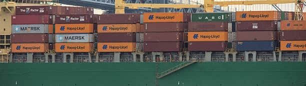 Side view of cargo ship loaded with shipping containers for overseas transport