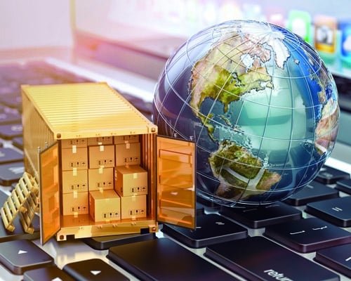 Miniature shipping container filled with boxes beside a globe resting on a computer keyboard, symbolizing digital freight management