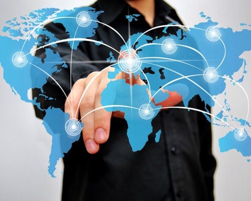 Hand touching a digital world map overlaid with network nodes and arcs illustrating international logistics connections