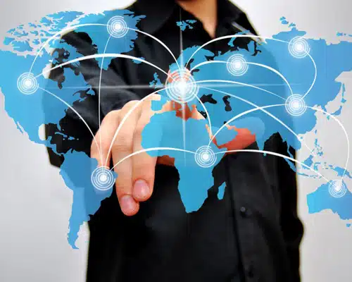 Hand touching a digital world map overlaid with network nodes and arcs illustrating international logistics connections