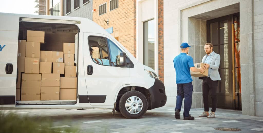 A delivery van with an open back filled with cardboard boxes, and a delivery person handing a package to a man at a doorstep, showcasing door-to-door shipping from China.