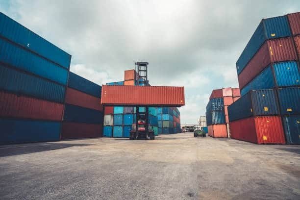 Forklift moving container in port terminal for international shipment