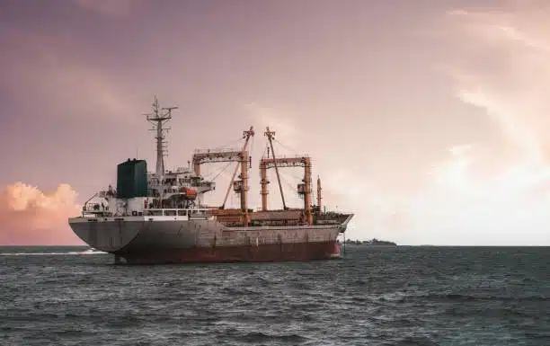 Cargo ship sailing in the ocean during sunset, transporting bulk freight