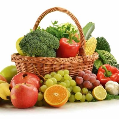 Wicker basket filled with fresh fruits and vegetables, including apples, grapes, broccoli, bell peppers, and corn