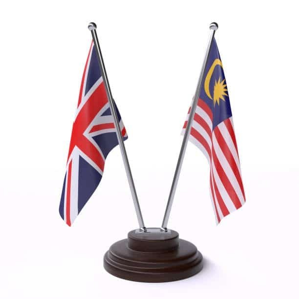 Miniature Malaysian and UK flags on a table stand, symbolizing bilateral trade and shipping