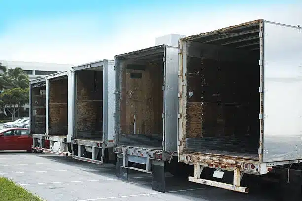 Multiple open delivery trucks awaiting shipment at logistics warehouse