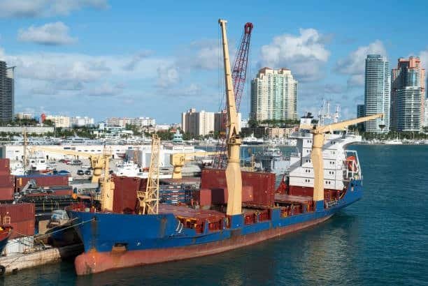 Container ship docked at a busy port with cranes loading cargo for shipment