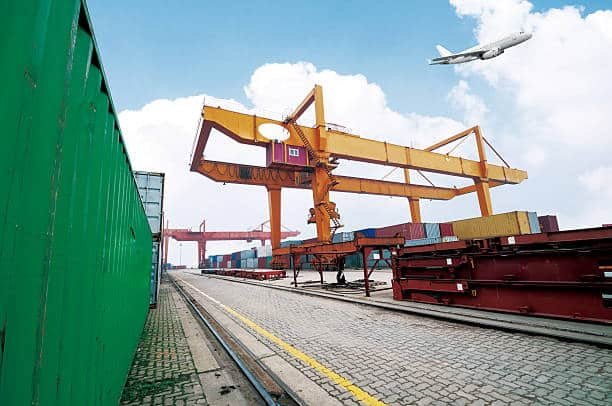 A port scene with a cargo ship and plane, essential for sea and air shipping to Côte d'Ivoire.