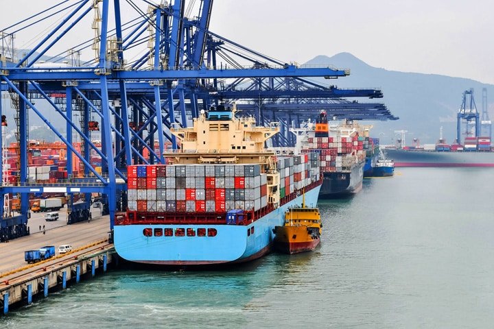 Navires porte-conteneurs à quai dans un terminal très fréquenté, avec des cargaisons transférées pour être livrées de porte à porte.