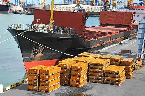 Cargo ship docked at port with large crates stacked on the dock for shipping