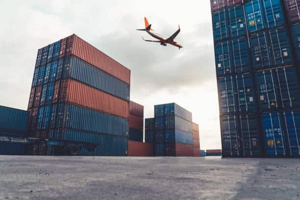 Cargo containers at shipping port with airplane in sky for overseas delivery