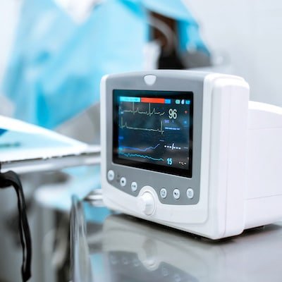 Close-up of a vital signs monitor displaying heart rate and ECG waveforms in a clinical setting