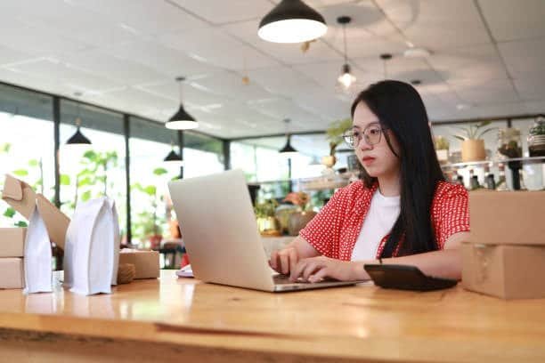Small business owner in Malaysia organizing package details for shipping to the UK