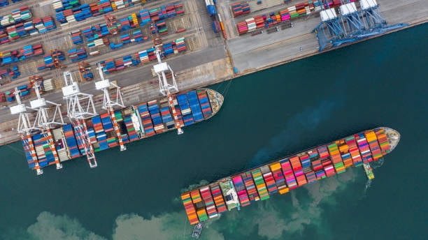 Aerial view of container ships docked at an ocean freight terminal, with cranes unloading cargo and port logistics in action