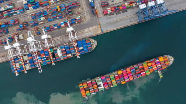 Aerial view of container ships docked at an ocean freight terminal, with cranes unloading cargo and port logistics in action