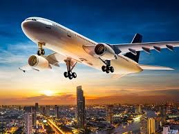 Airplane flying over a city at sunset, representing international air freight to Qatar.
