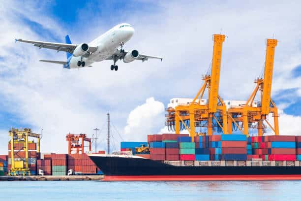 Airplane above shipping containers and cranes at port, highlighting international shipping to Belgium.