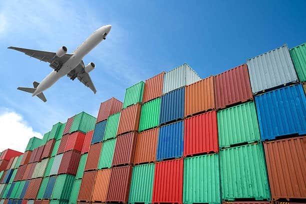 Airplane flying above stacked cargo containers, symbolizing fast air freight services from China to Algeria