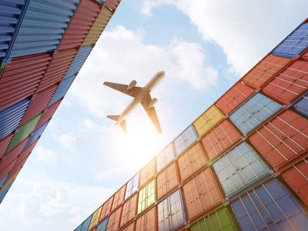 Airplane flying above colorful stacked shipping containers, representing air cargo from China to Bangladesh