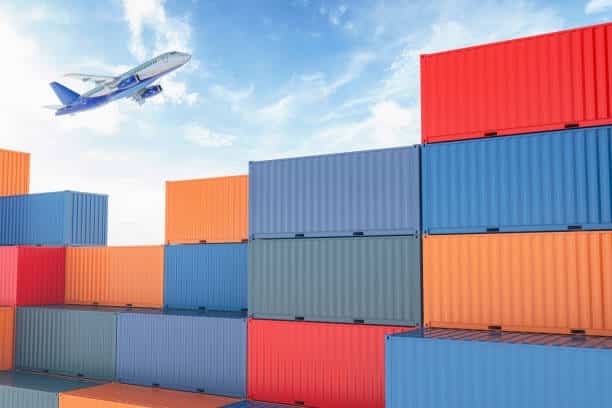 Airplane flying above stacked shipping containers for export to Sudan