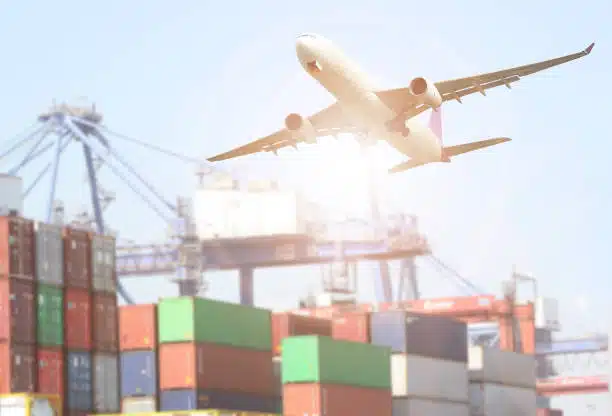 Airplane taking off above stacked shipping containers for air freight to Kenya.