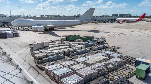 Cargo stacked at airport with freight aircraft ready for loading from China to India