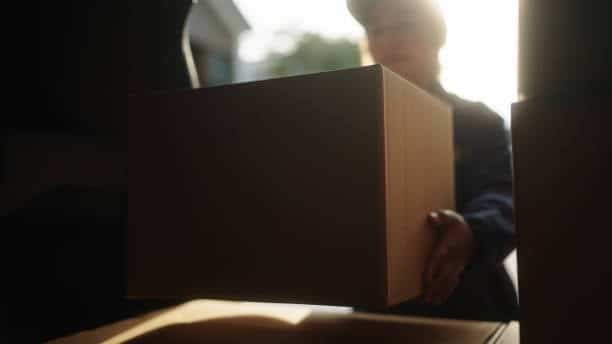 Person loading a cardboard box into a delivery van symbolizing Alibaba order shipping