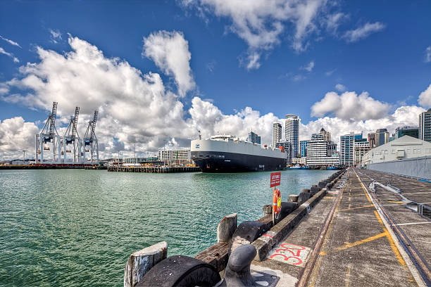 Freight vessel docked at Auckland port with container cranes and cityscape