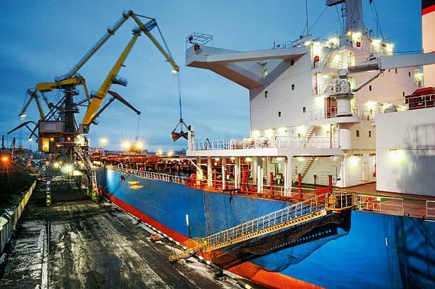 Bulk cargo being loaded onto ship at FOB origin port using dockside cranes