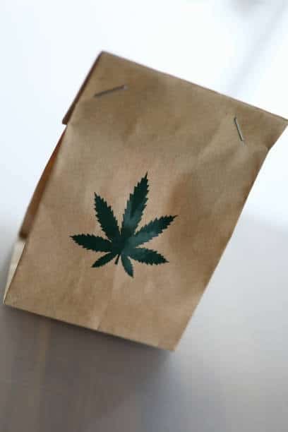 Brown paper bag with cannabis leaf symbol printed on the front