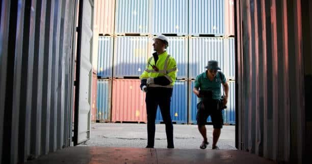 Logistic inspector checking cargo documentation inside a freight container