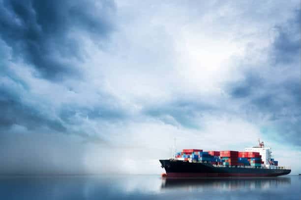 Cargo vessel navigating through storm clouds at sea