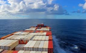 Rear view of a cargo vessel carrying containers from China to Indonesia over open sea.