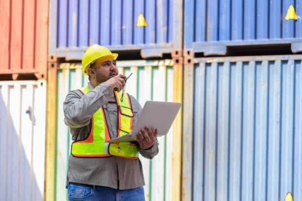 Shipping supervisor communicating at a freight yard, managing container scheduling and overseas shipping times.