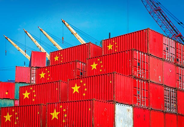 Red containers marked with Chinese flags being prepared for international shipment