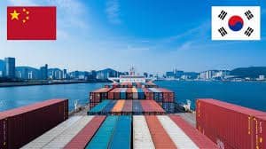 Freight containers on a ship sailing from China to South Korea with national flags.