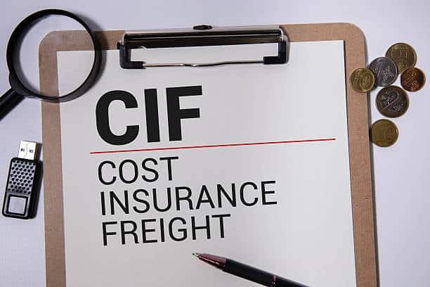 CIF (Cost Insurance Freight) printed on a clipboard with pen, USB, and coins on a desk