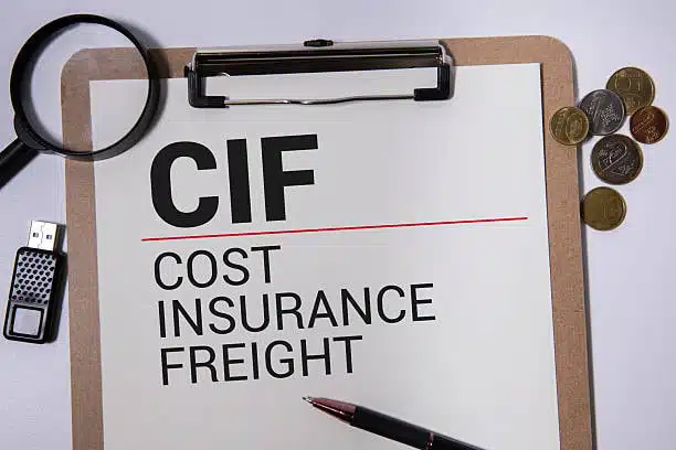 CIF (Cost Insurance Freight) dicetak pada papan keratan dengan pen, USB dan syiling di atas meja