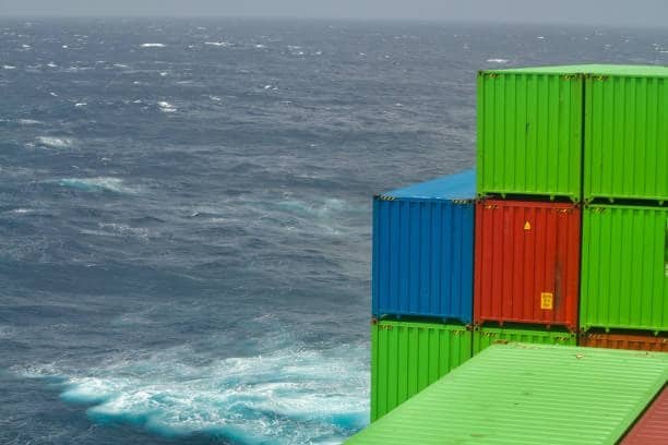 Stacked green, red, and blue containers on cargo vessel in the open ocean