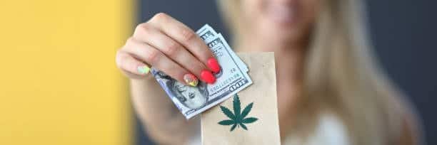 Woman holding dollar bills and a paper bag with cannabis leaf—potential confusion with THC in shipping