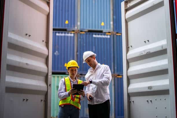 Two workers inspecting documents inside a cargo container for export to Mauritania