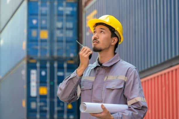 Port inspector coordinating with teams to monitor container handling and track overseas shipping duration.