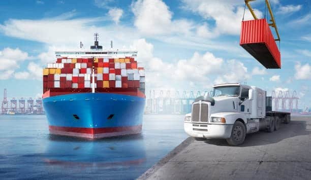 Container vessel at seaport with a drayage truck and crane in action, demonstrating port-to-warehouse freight movement.