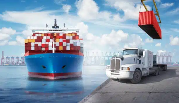 Container vessel at seaport with a drayage truck and crane in action, demonstrating port-to-warehouse freight movement.