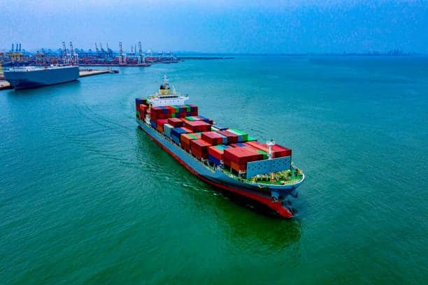 Full view of container vessel cruising in Singapore harbor