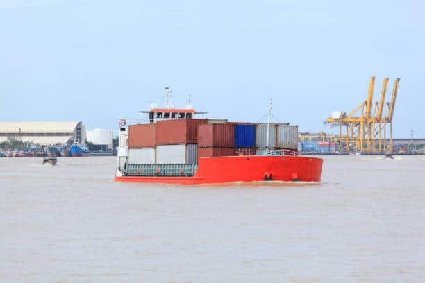 Freight vessel carrying shipping containers at harbor, bound for the UAE.
