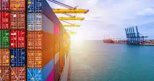 Side view of container vessel at port with cranes loading cargo for shipping to Jordan.